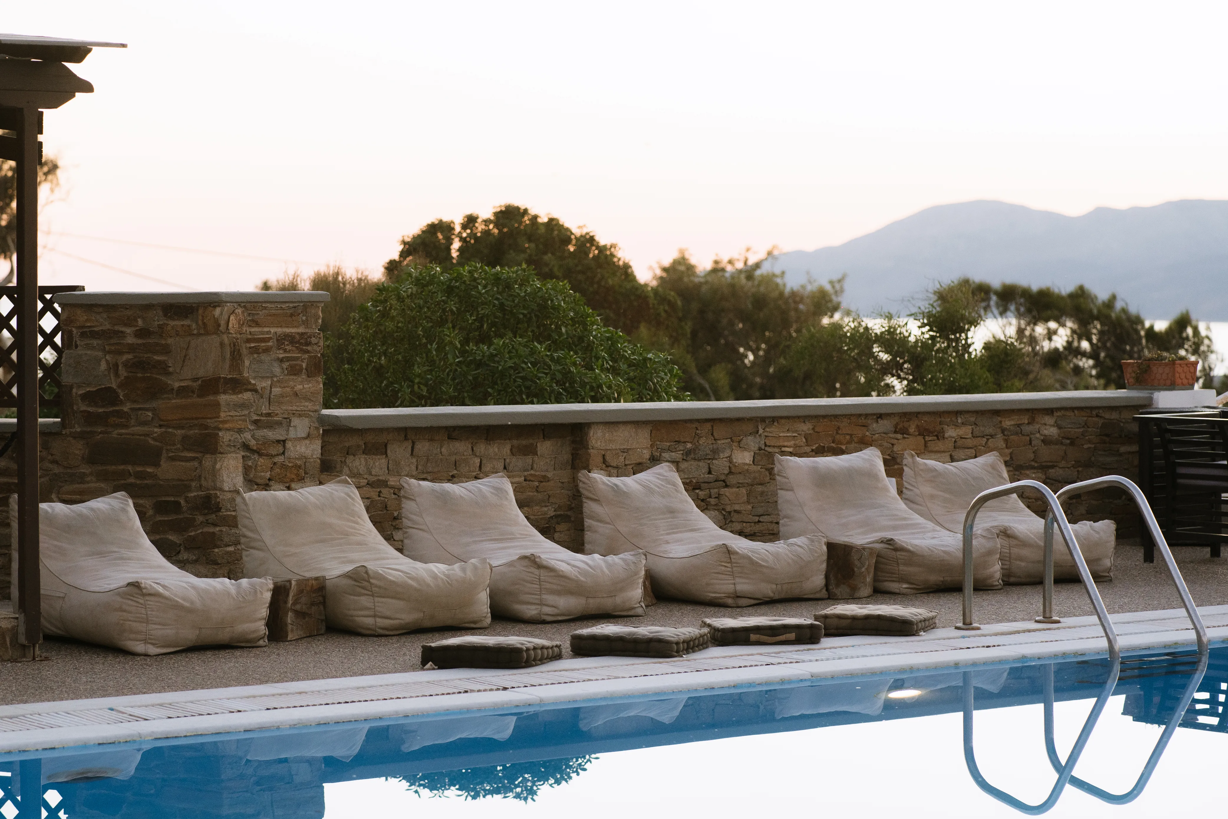 SkalaSunset comfort studio sunbeds and pool with mountain backdrop in Ios