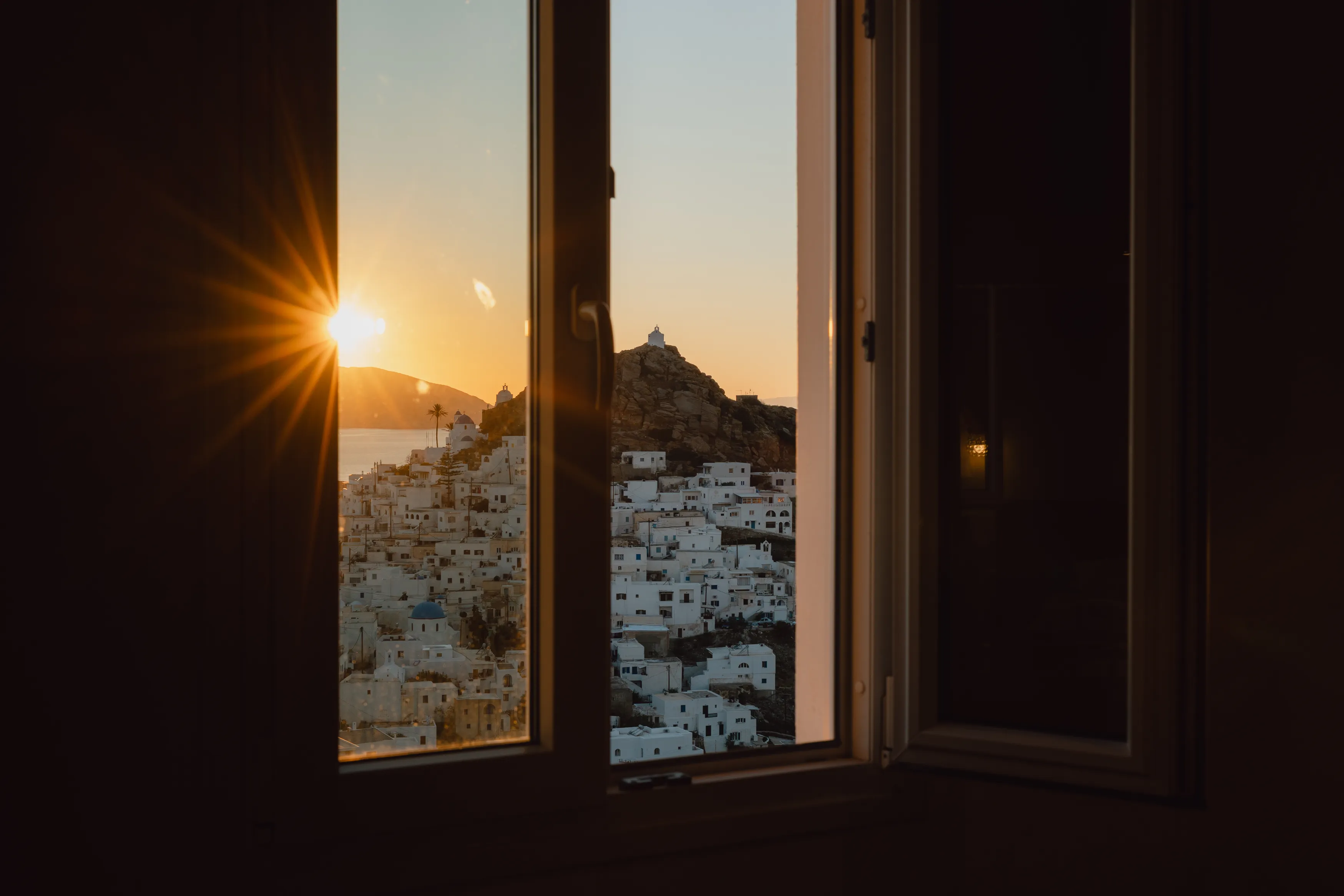 SkalaSunset deluxe double room window framing sunrise over Chora Ios